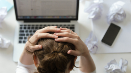portrait-woman-grabbing-head-desk-near-laptop