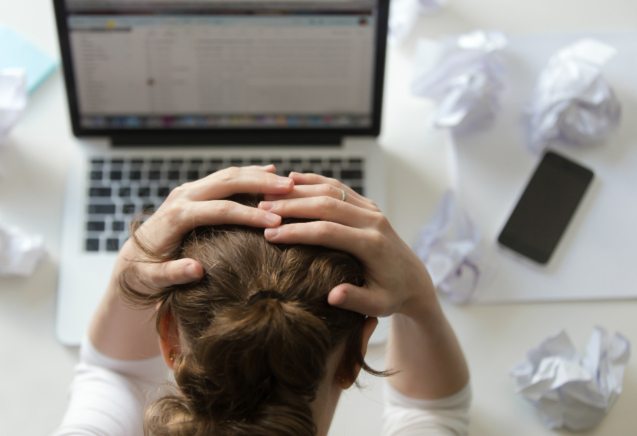portrait-woman-grabbing-head-desk-near-laptop